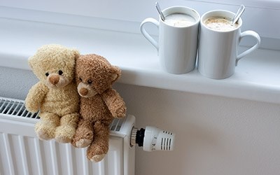 To bamser sidder på en radiator med to kopper